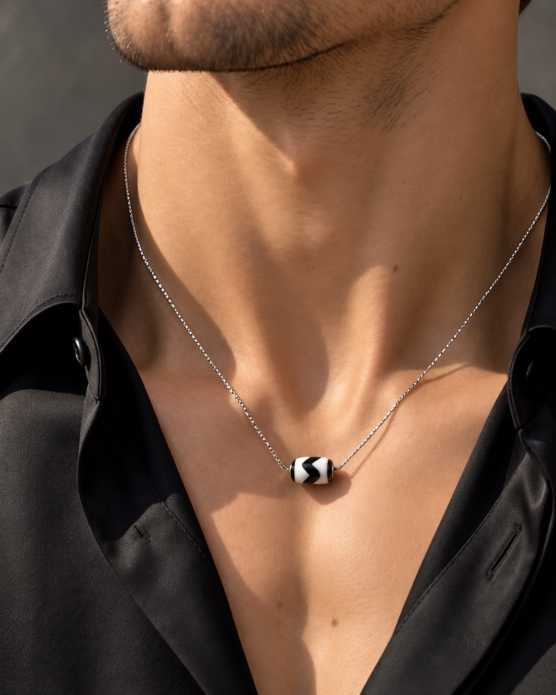 Male model wearing the Tiger Tooth Dzi necklace in black tailoring
