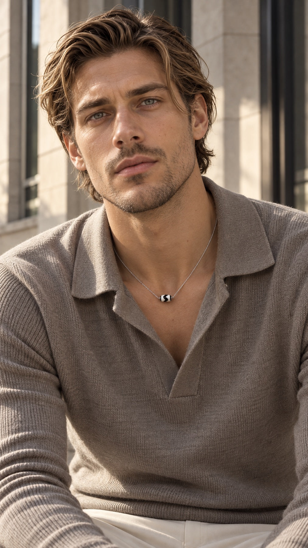 Male model wearing a Tiger Tooth Dzi necklace with a taupe knit polo